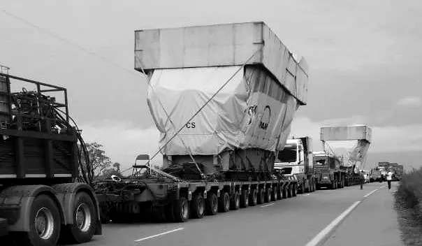Un convoi de semi-remorques surbaissées transporte de volumineux équipements bâchés sur une route nationale, le type de matériel lourd au cœur de l'affaire des groupes électrogènes d'EDM-SA.