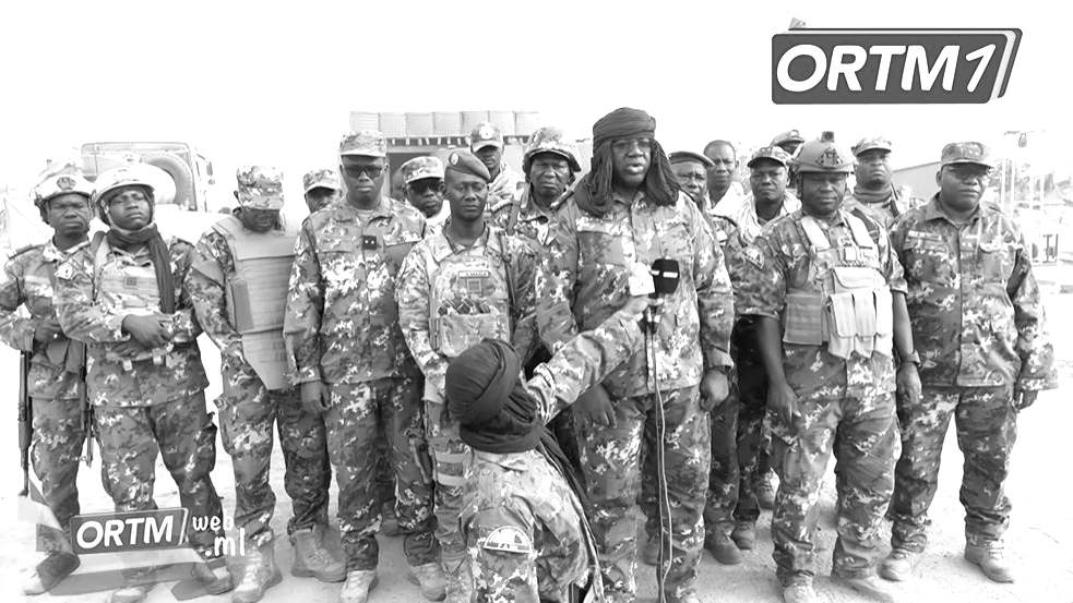 Un groupe d'officiers et de soldats maliens en tenue de camouflage, dont un officier coiffé d'un turban qui s'exprime devant un micro tendu, lors d'une déclaration filmée par l'ORTM.