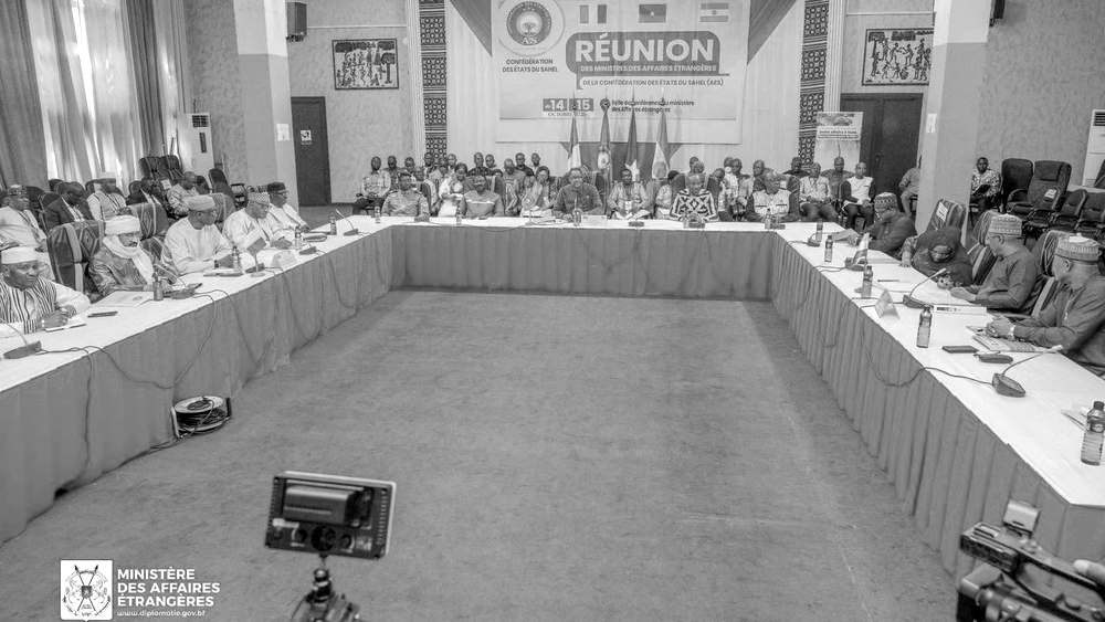 Les délégations de la Confédération des États du Sahel réunies autour d'une table en U lors de la réunion des ministres des Affaires étrangères de l'AES, sous une banderole aux couleurs des trois pays.